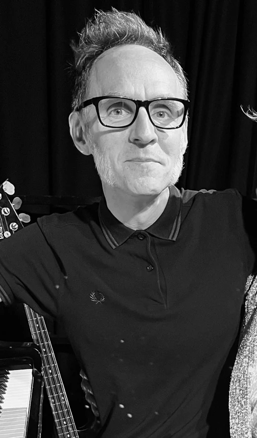 Jason Frederick, photographed in the dark beside a guitar